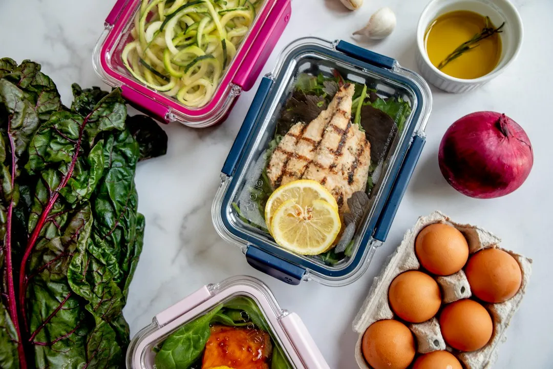 Person preparing meal prep containers with proteins, vegetables, and grains